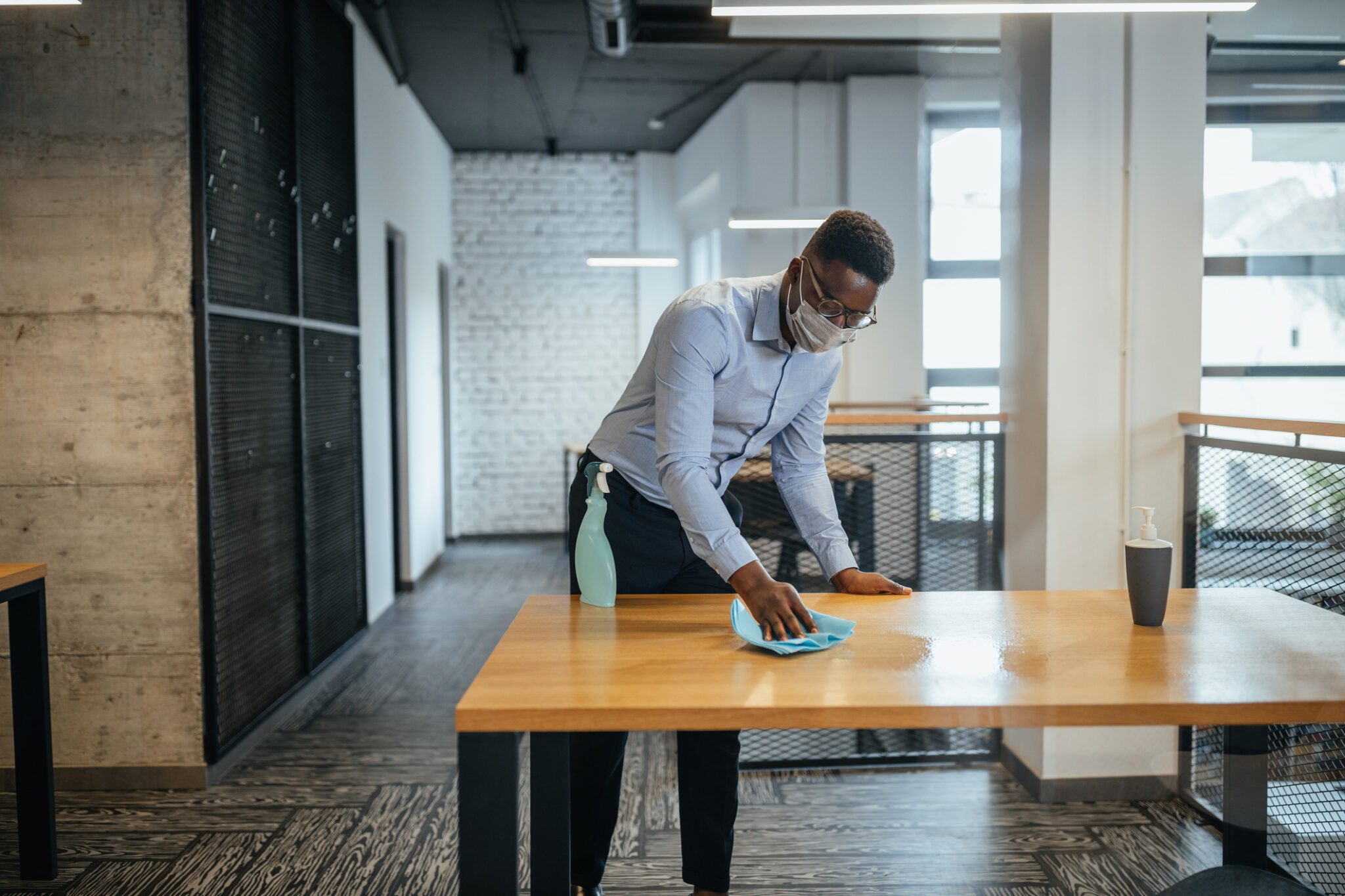 Man sanitizing workspace in office