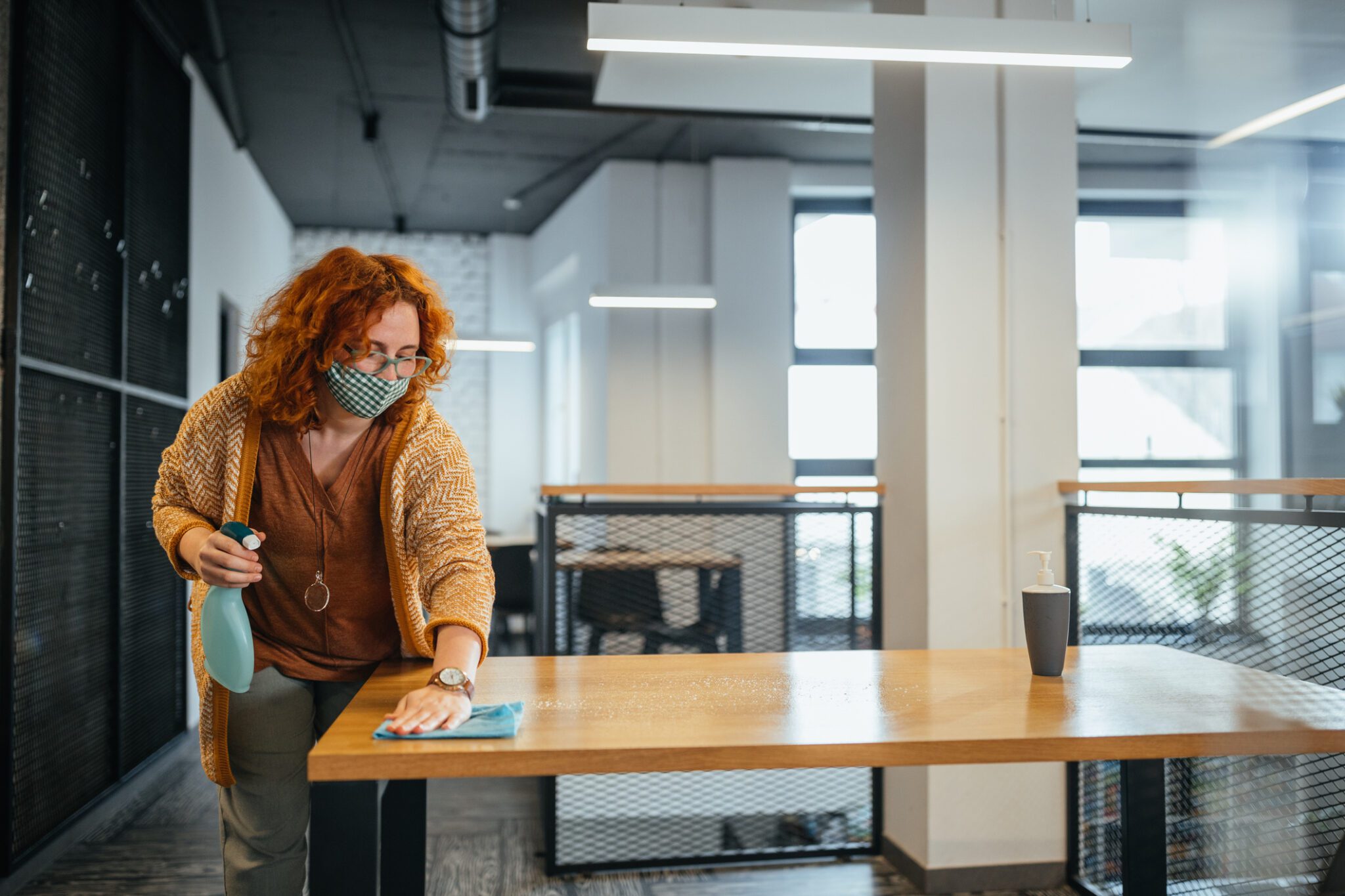 Woman cleaning table with spray bottle